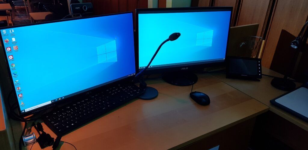 The speaker desk, with two screens, a desk microphone, and a web camera above the screen to the left.